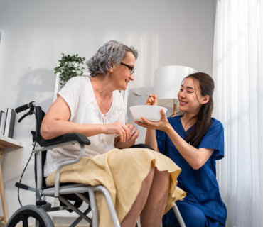 a health professional woman assist a senior woman to eat