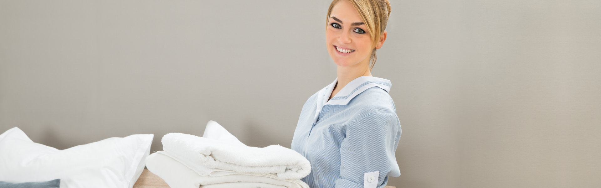 A woman holding a stack of white towels.