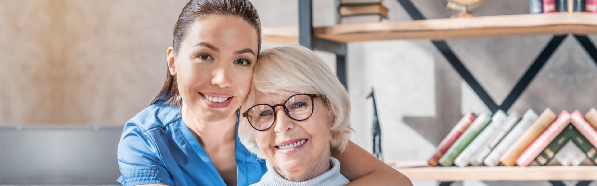 A younger woman lovingly hugs an elderly woman.